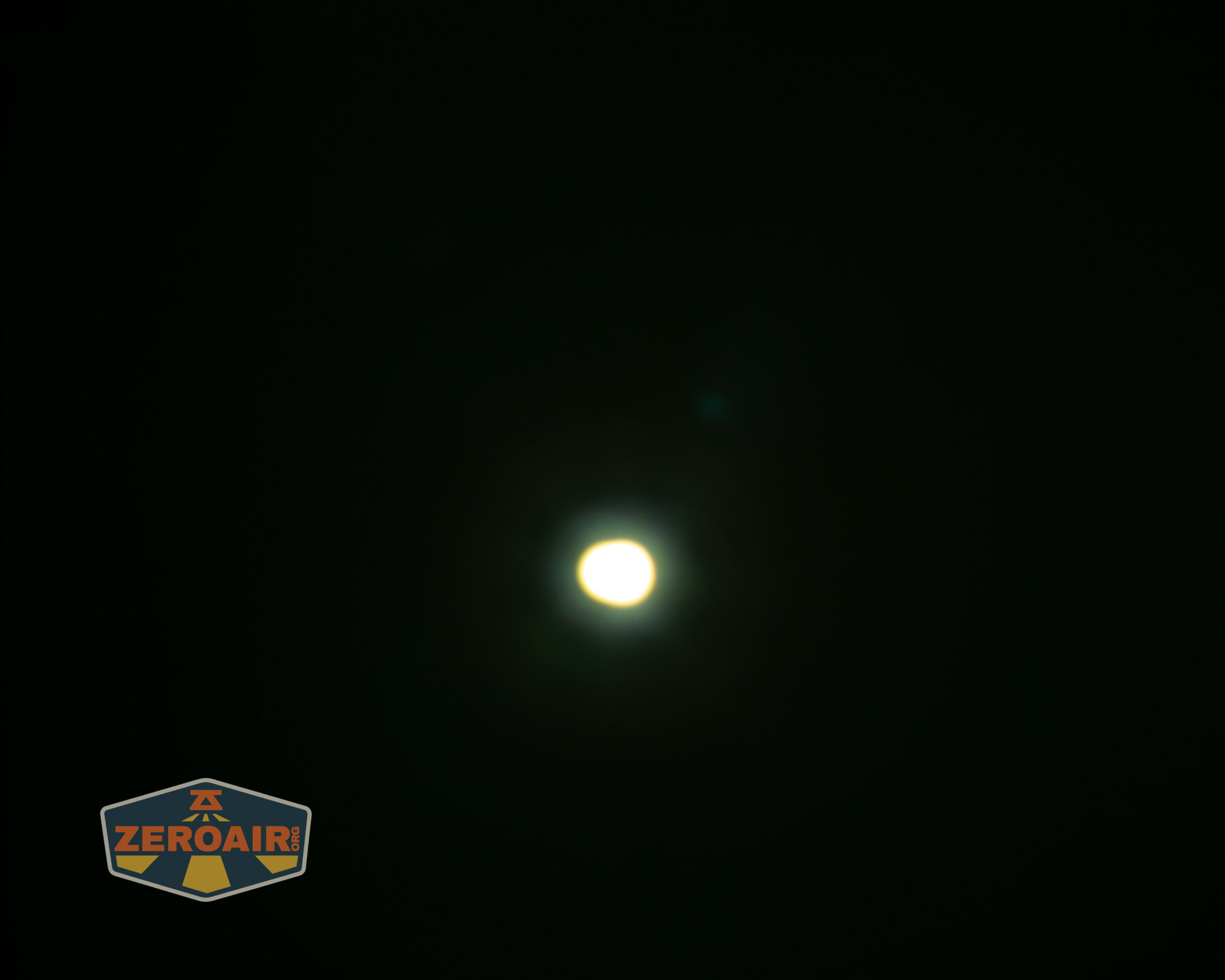 A bright white circular light is centered against a dark background. The ZeroAir logo is visible in the bottom left corner.