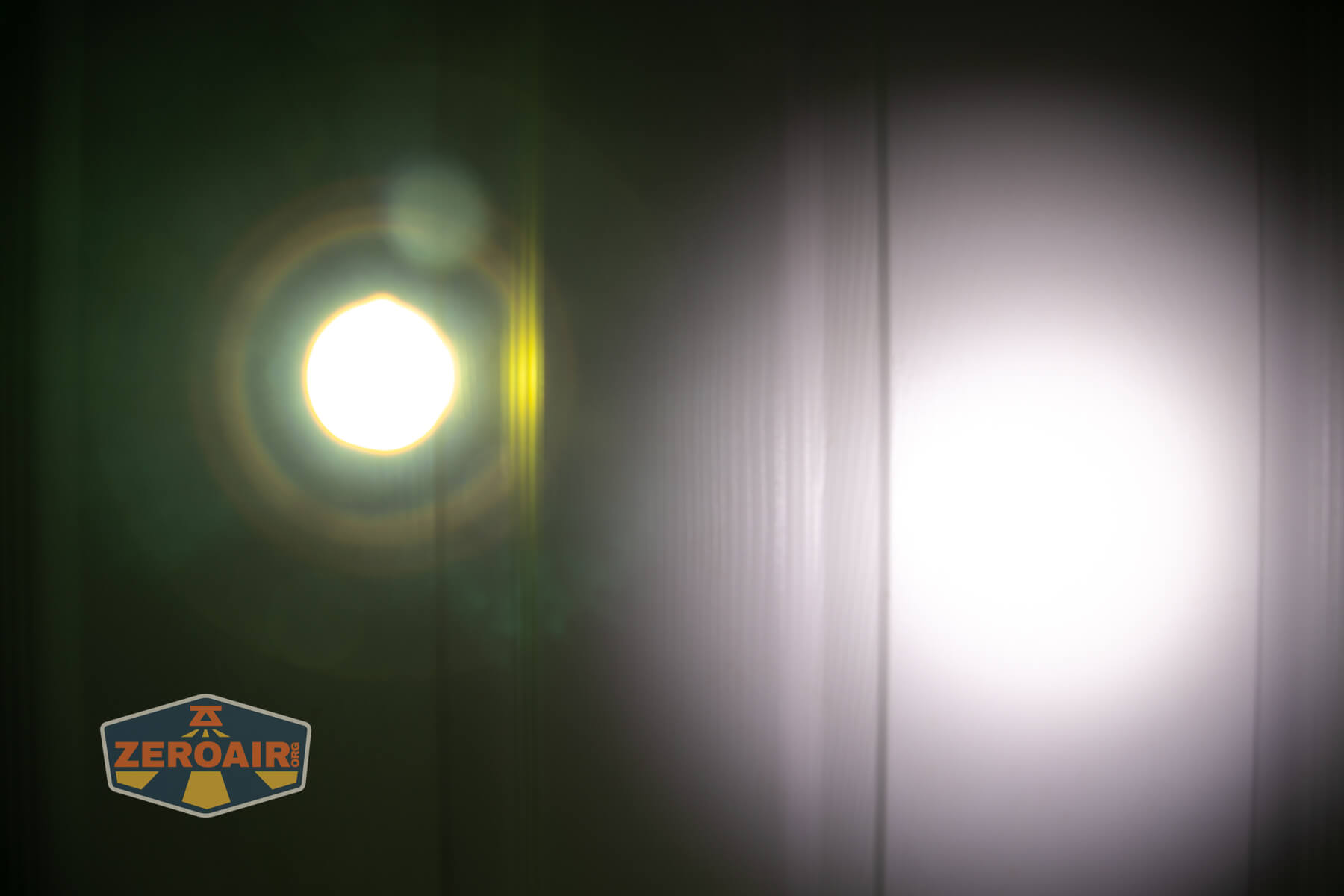 A bright circular light on the left and a larger, diffused white light on the right are projected onto a vertical, paneled surface. The ZeroAir logo appears in the bottom left corner.