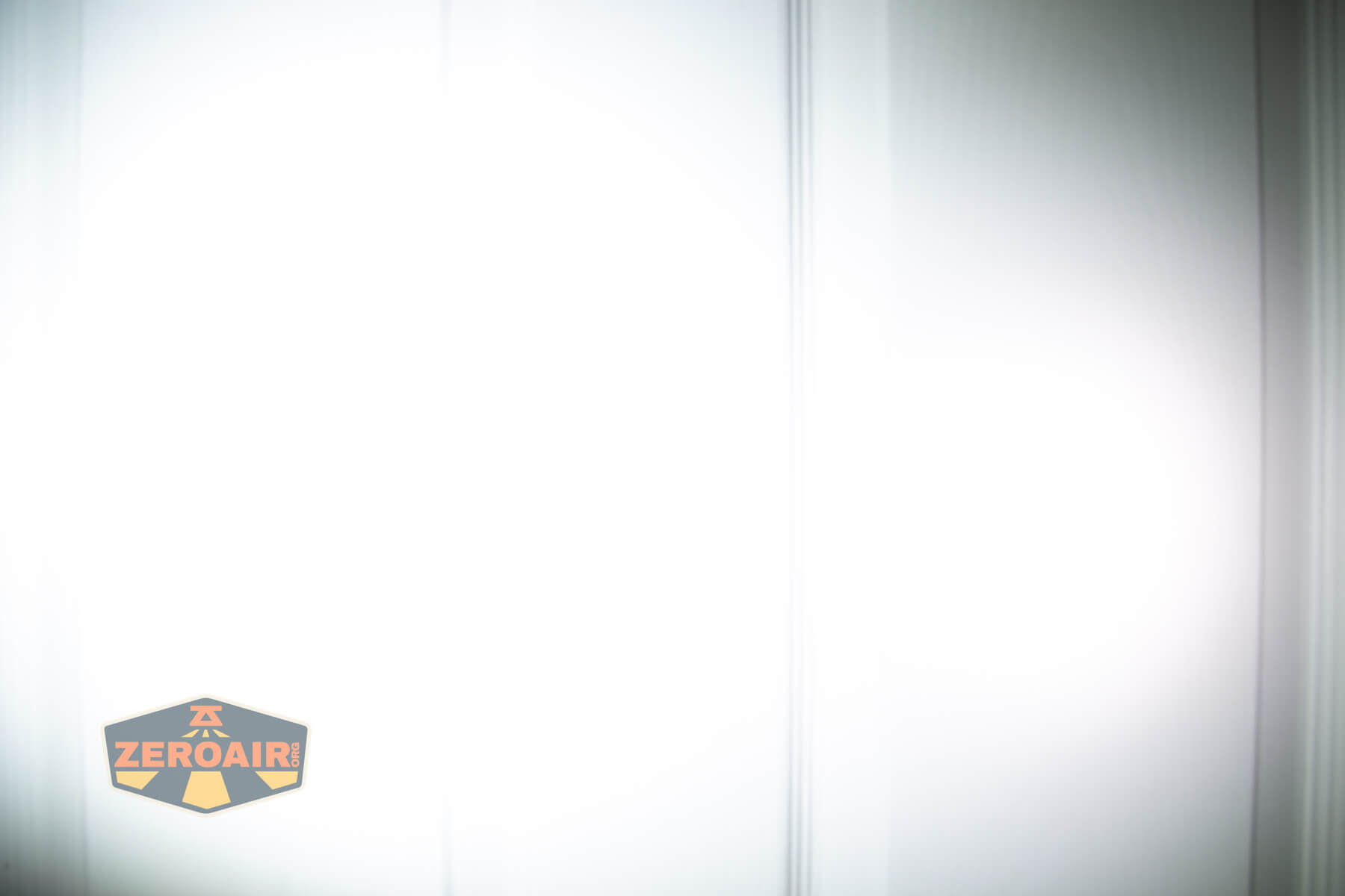 A white surface with vertical lines and a faint gradient, with a ZeroAir logo in the bottom left corner.