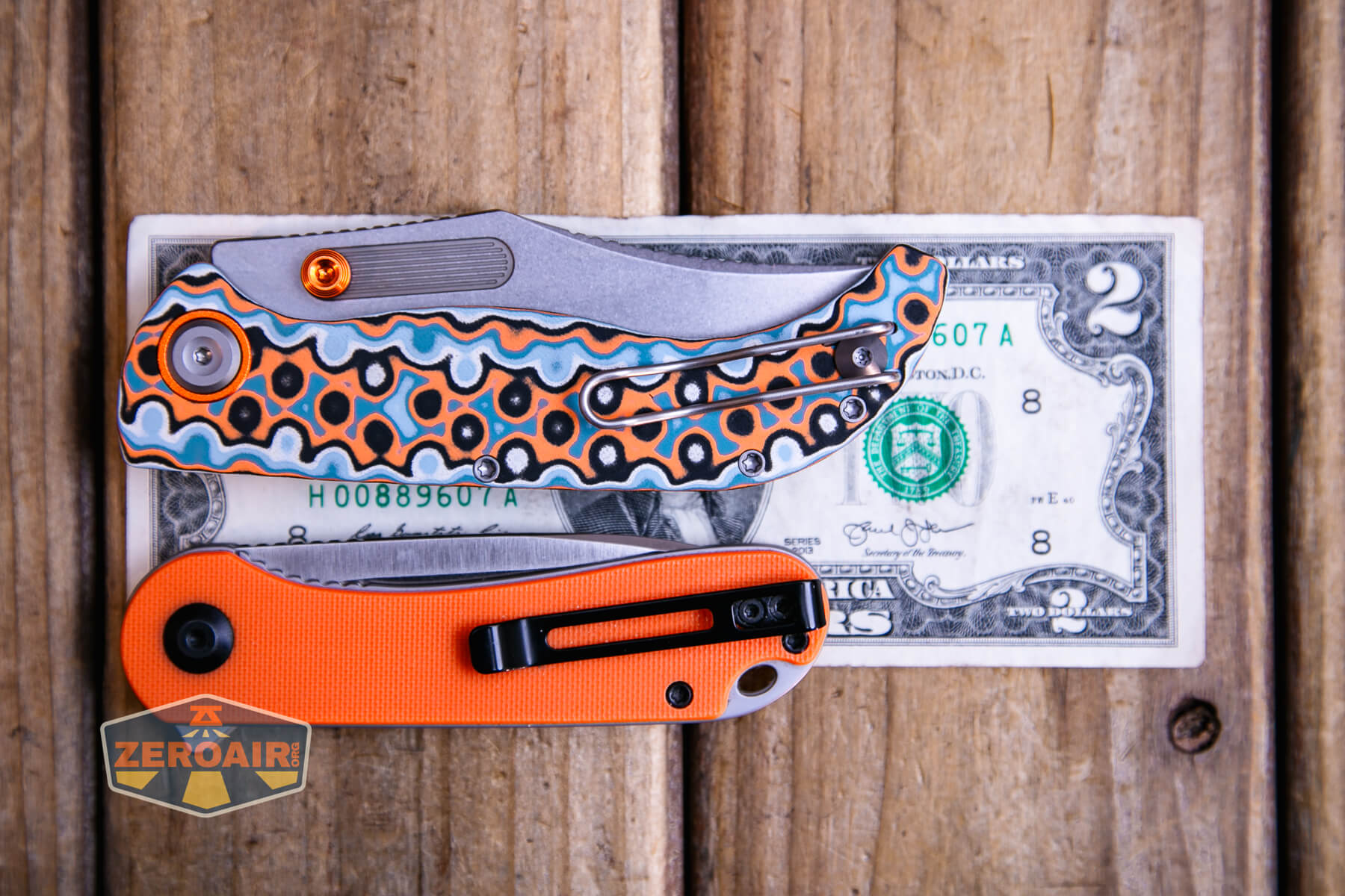 Vosteed Naga S35VN knife on a two dollar bill compared to Civivi Elementum in orange