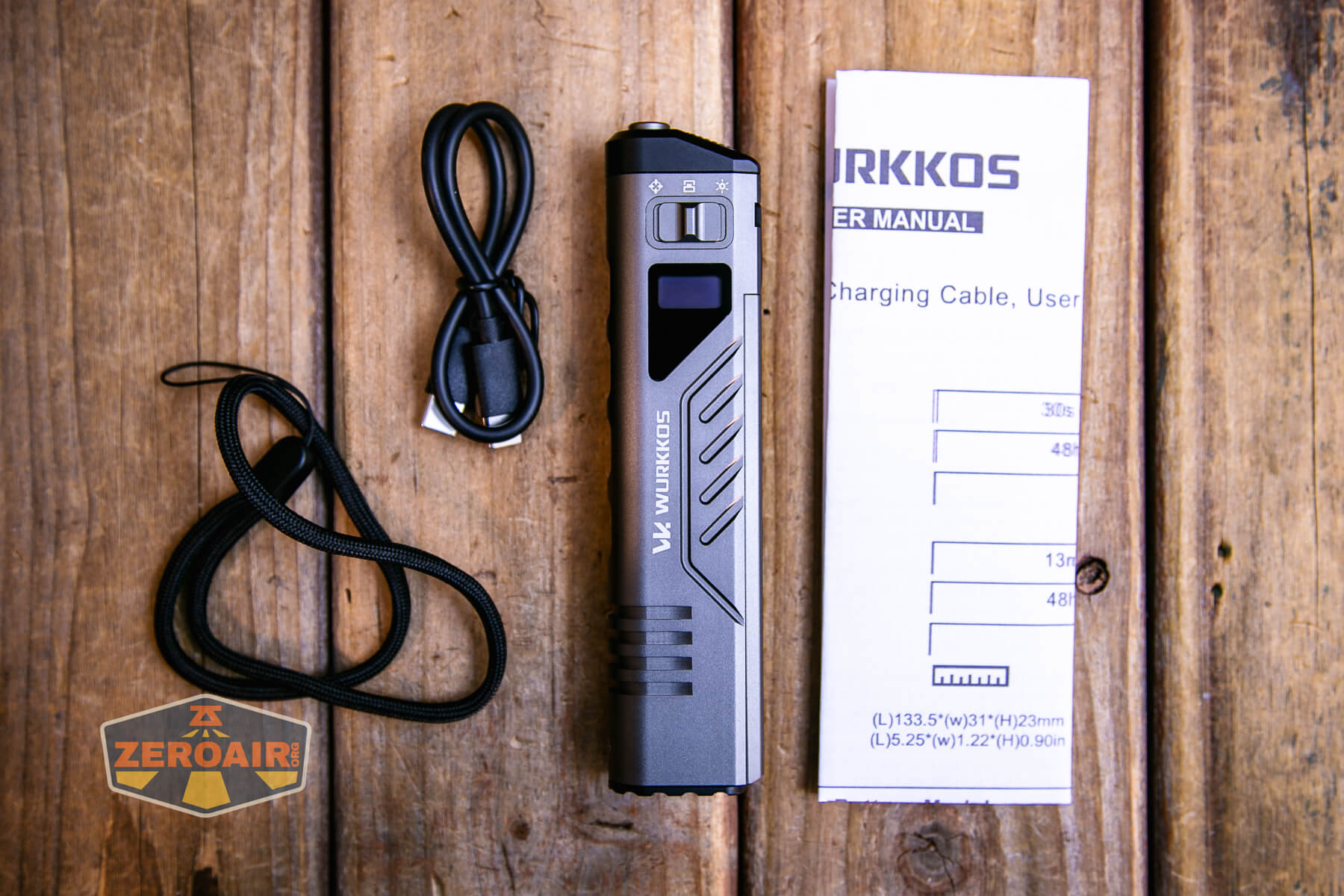 A Wurkkos flashlight, a USB charging cable, a wrist strap, and a folded user manual are arranged on a wooden surface. The ZeroAir logo is visible in the bottom left corner.