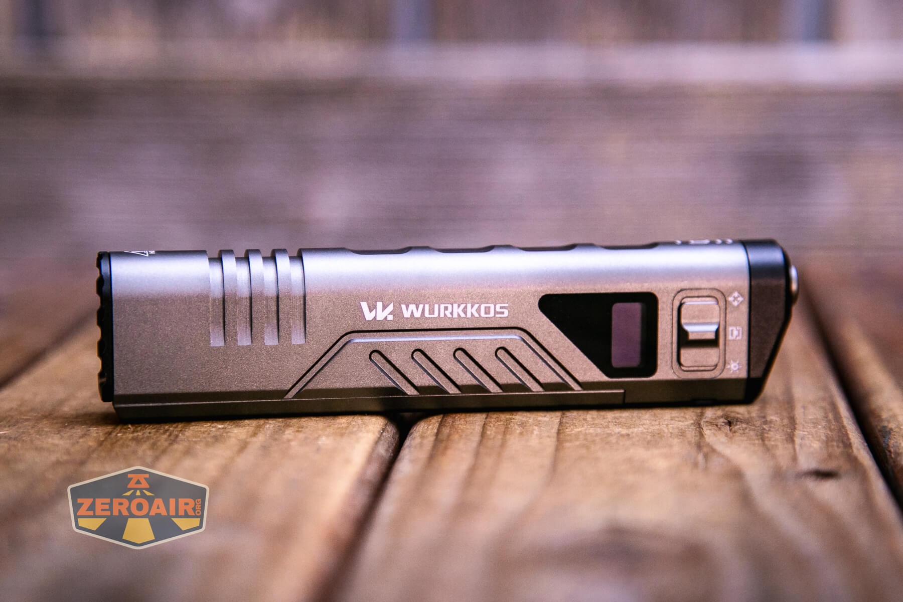 A Wurkkos-branded grey rectangular flashlight with a digital display and side buttons rests on a wooden surface. The ZeroAir logo is visible in the bottom left corner of the image.