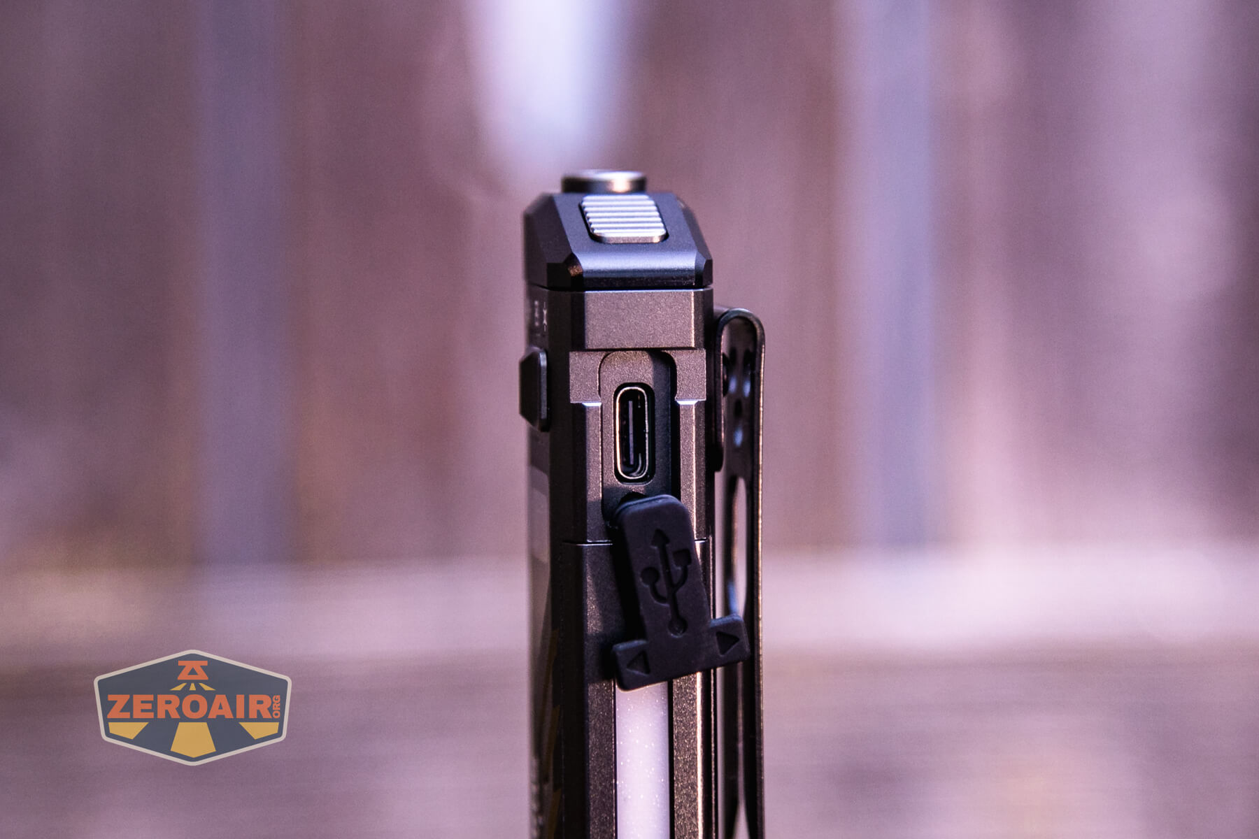 A close-up view of an electronic device showing a USB-C port and a removable USB cover on the side. The background is blurred, and a ZeroAir logo is visible in the lower left corner.