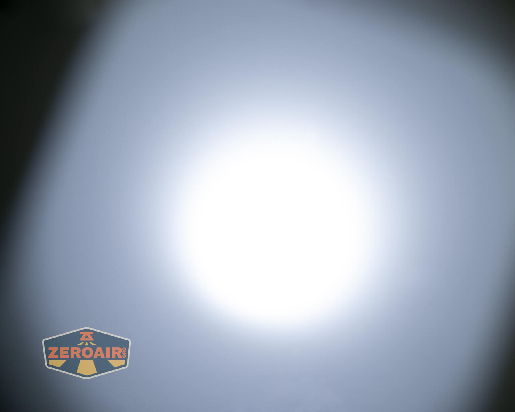 A bright white circular light shines in the center against a gray background, creating a gradient effect. A ZeroAir logo appears in the bottom left corner of the image.