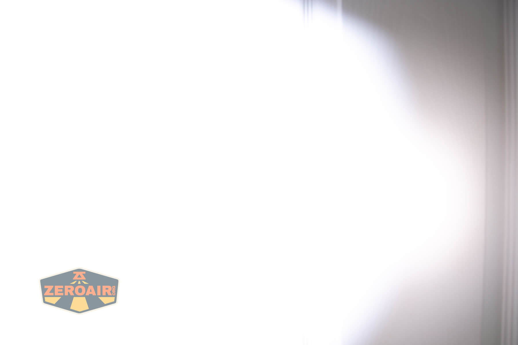 A bright white light creates a large illuminated area with soft edges against a smooth, grayish background. In the lower left corner, a logo with the text ZEROAIR is visible.