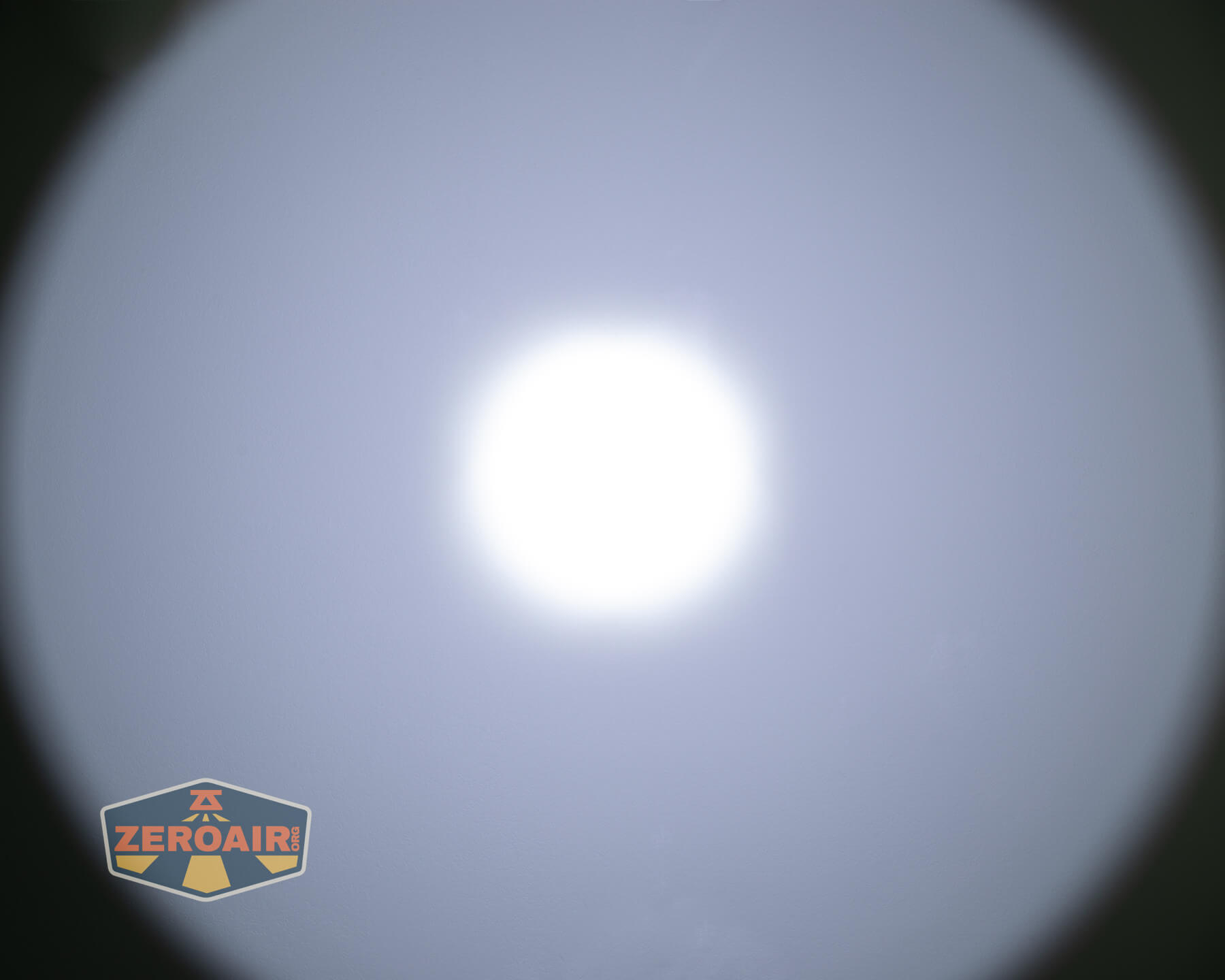 A bright, white circular light is centered against a gray background, creating a gradient effect. The ZeroAir logo appears in the lower left corner of the image.