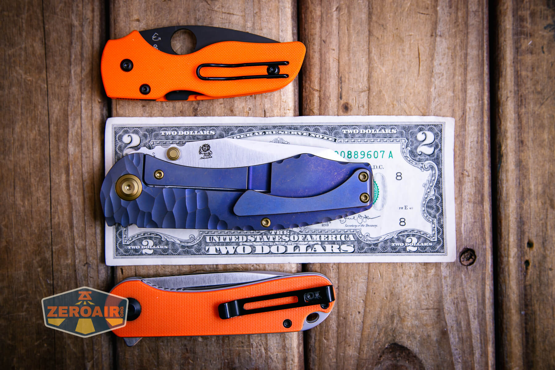 Kansept Caveman frame lock knife on a two dollar bill compared to Civivi Elementum in orange with Spyderco