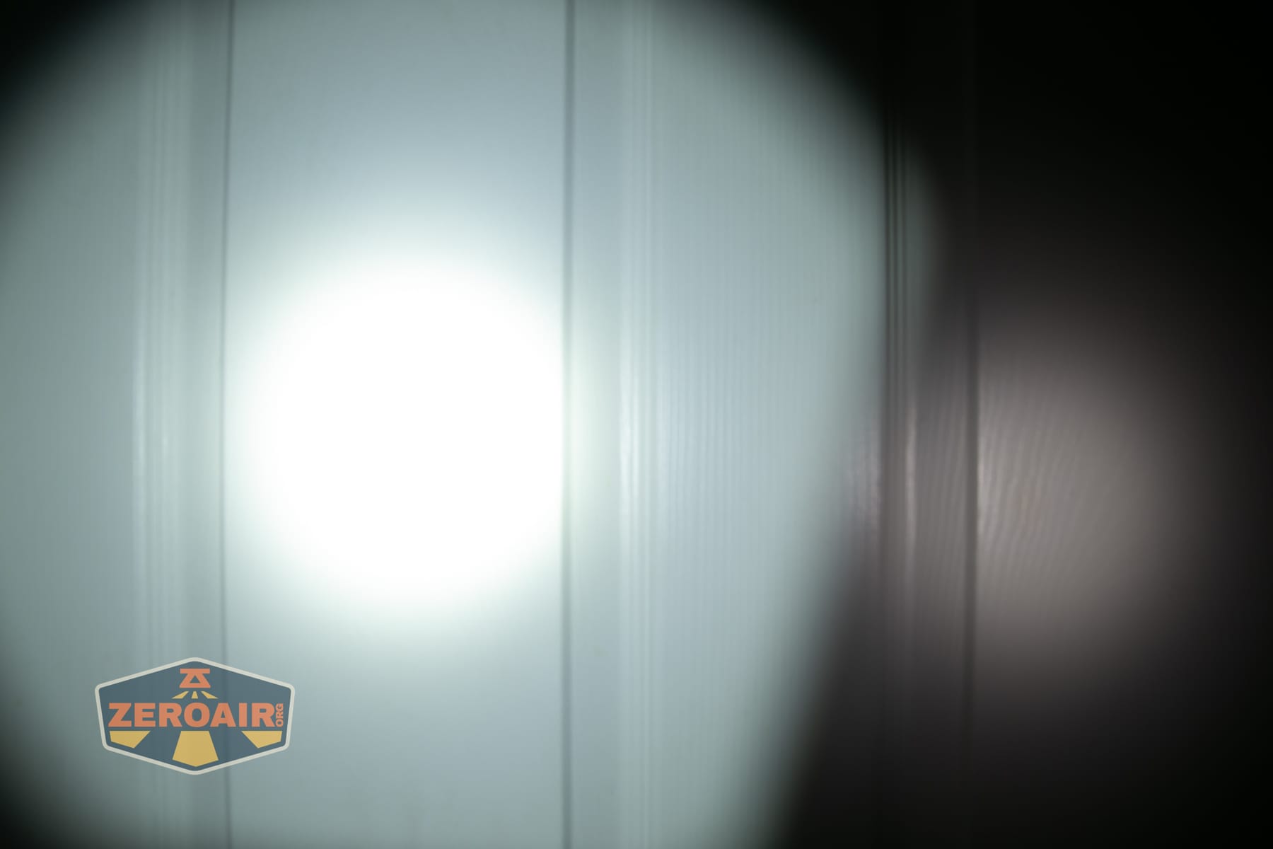 Olight ArkPro Ultra Onyx Black flashlight beamshots on door (at 1') compared to nichia 219b 4500K