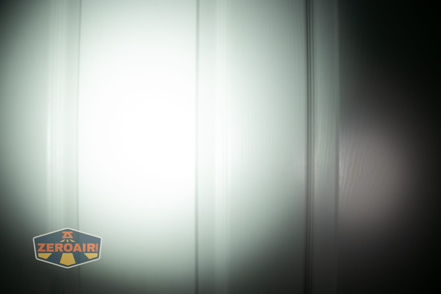 Olight ArkPro Ultra Onyx Black flashlight beamshots on door (at 1') compared to nichia 219b 4500K