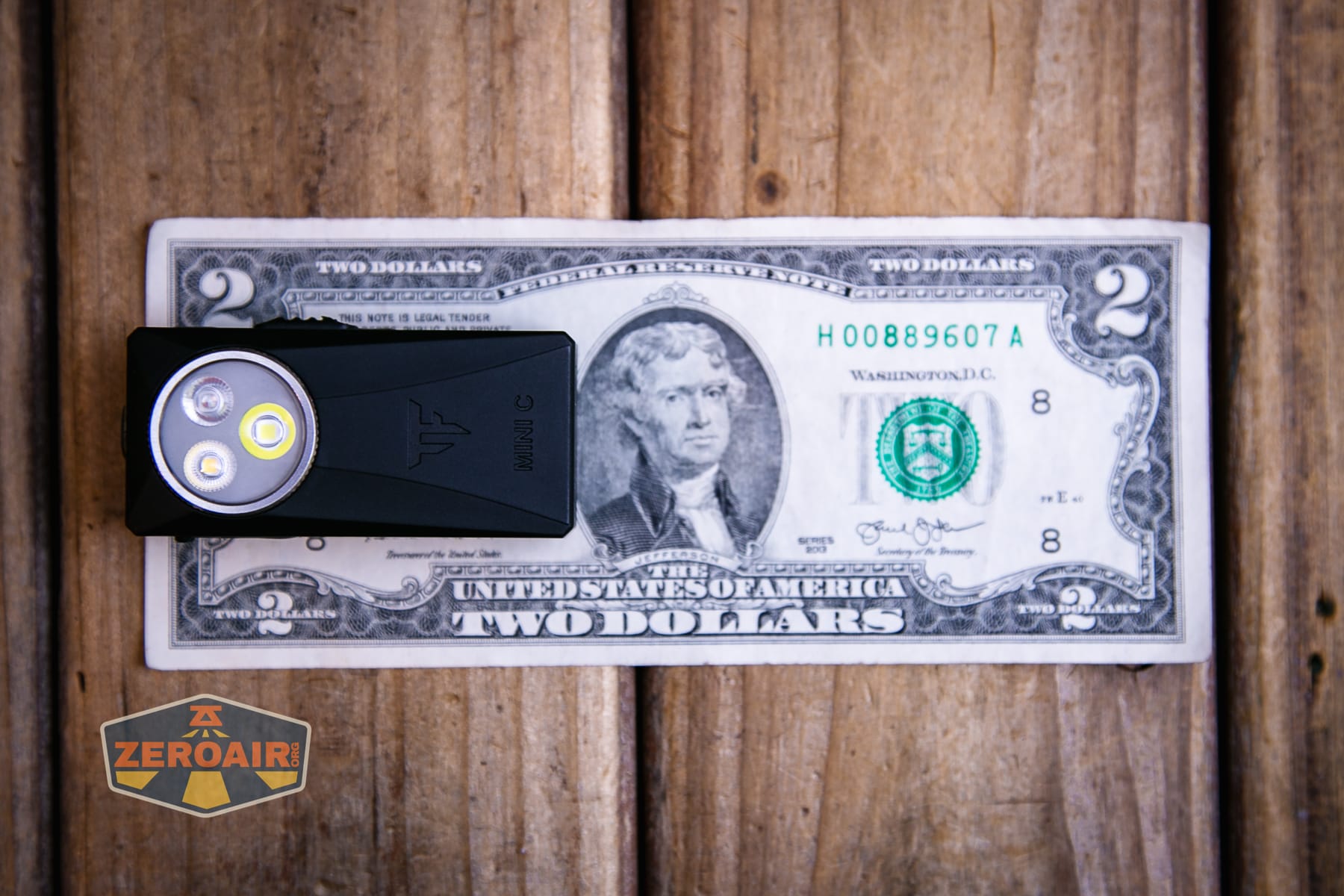 Trustfire Mini C Multifunctional clip-on flashlight on a two dollar bill
