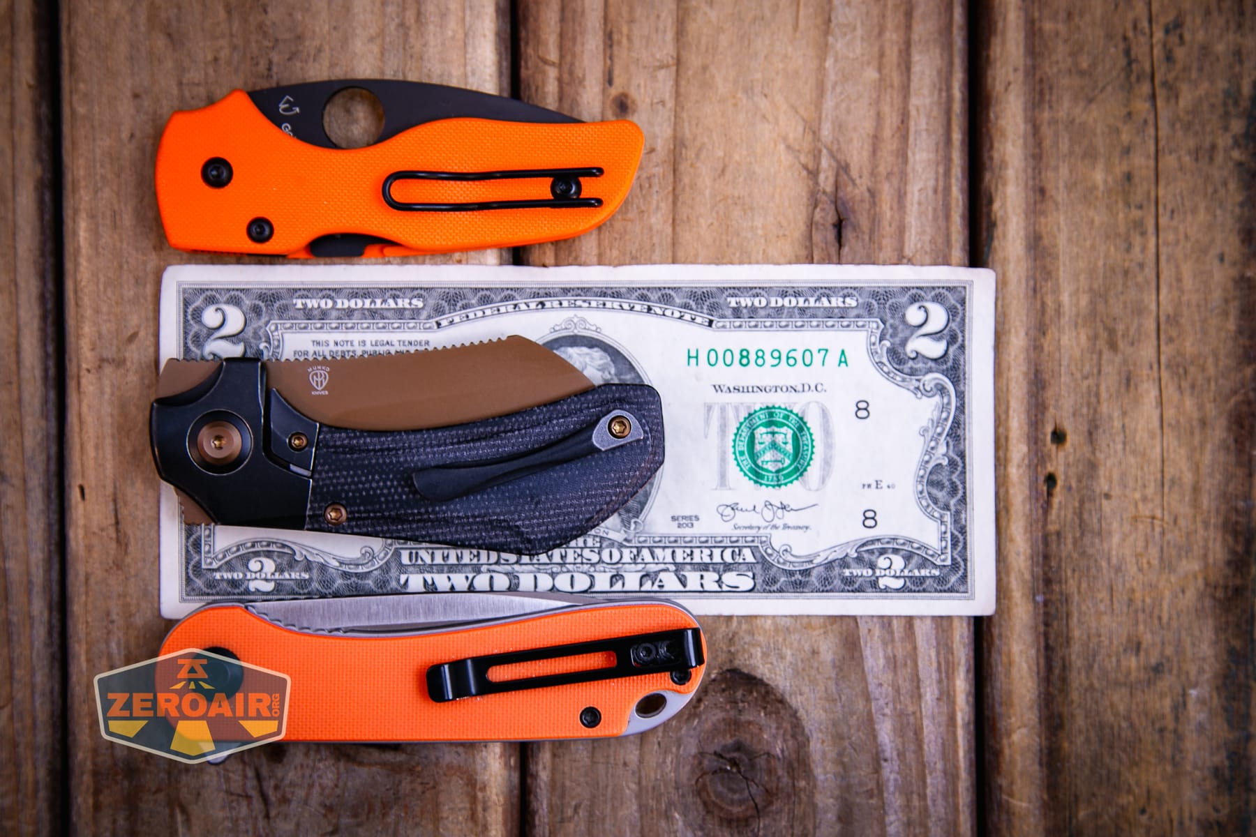 Kansept Pluto S90V knife on a two dollar bill compared to Civivi Elementum in orange