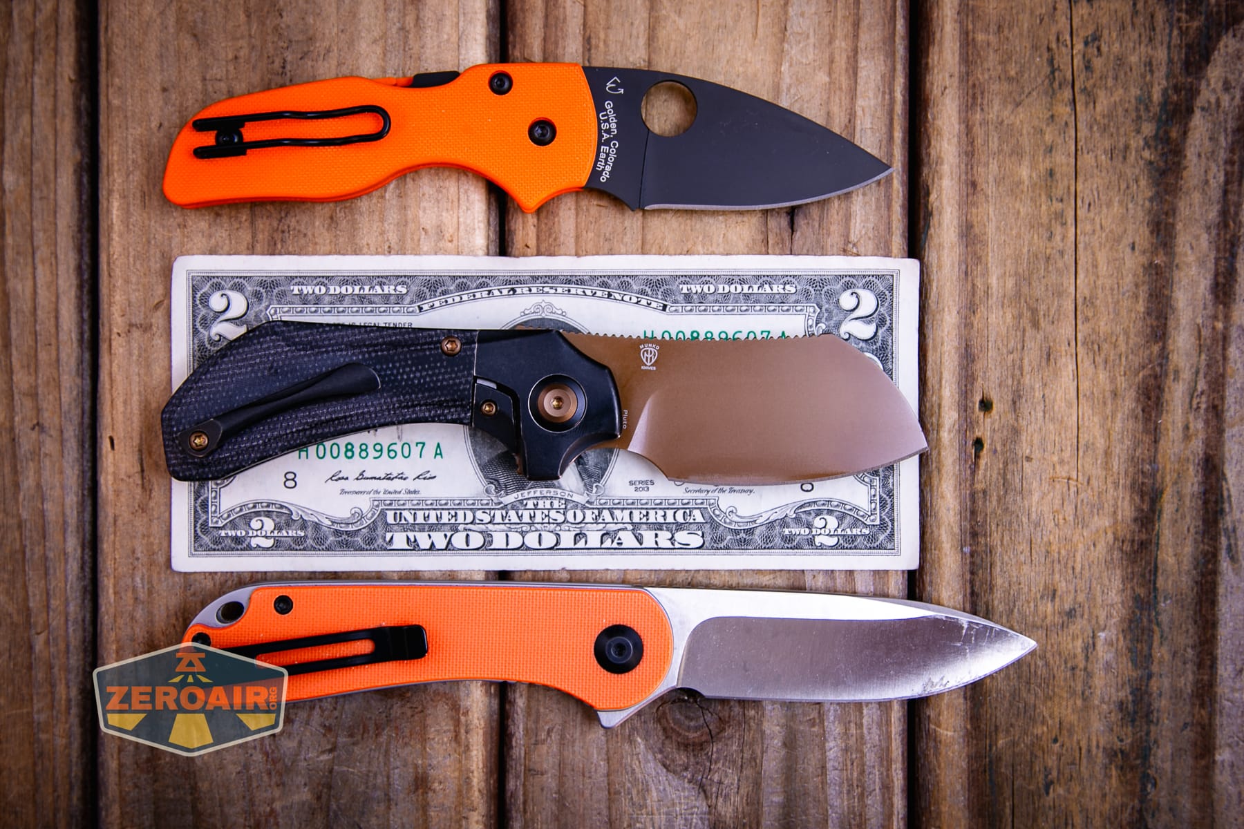 Kansept Pluto S90V knife on a two dollar bill compared to Civivi Elementum in orange
