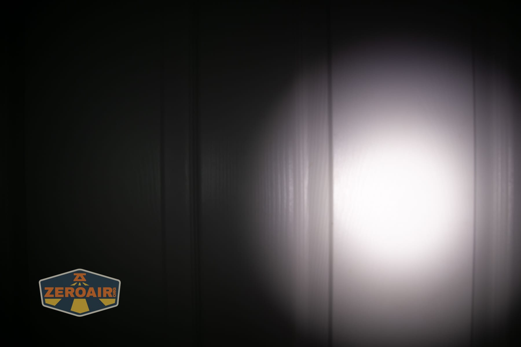 Olight Arkpro Stars and Stripes flat flashlight beamshots on door compared to Nichia 219b