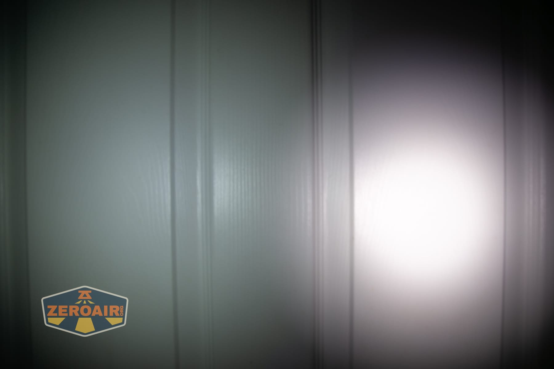 Olight Arkpro Stars and Stripes flat flashlight beamshots on door compared to Nichia 219b