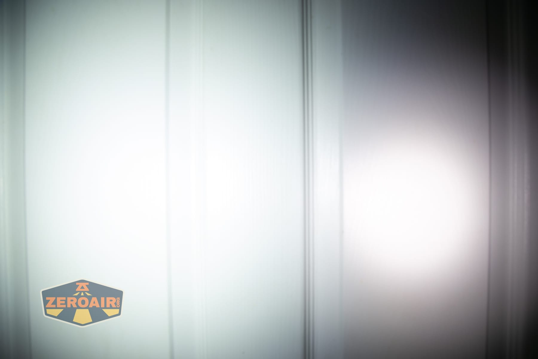 Olight Arkpro Stars and Stripes flat flashlight beamshots on door compared to Nichia 219b