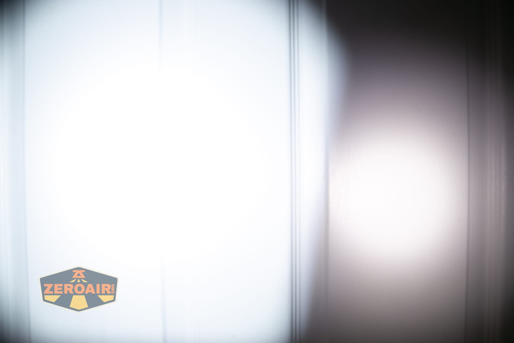 Olight Arkpro Stars and Stripes flat flashlight beamshots on door compared to Nichia 219b