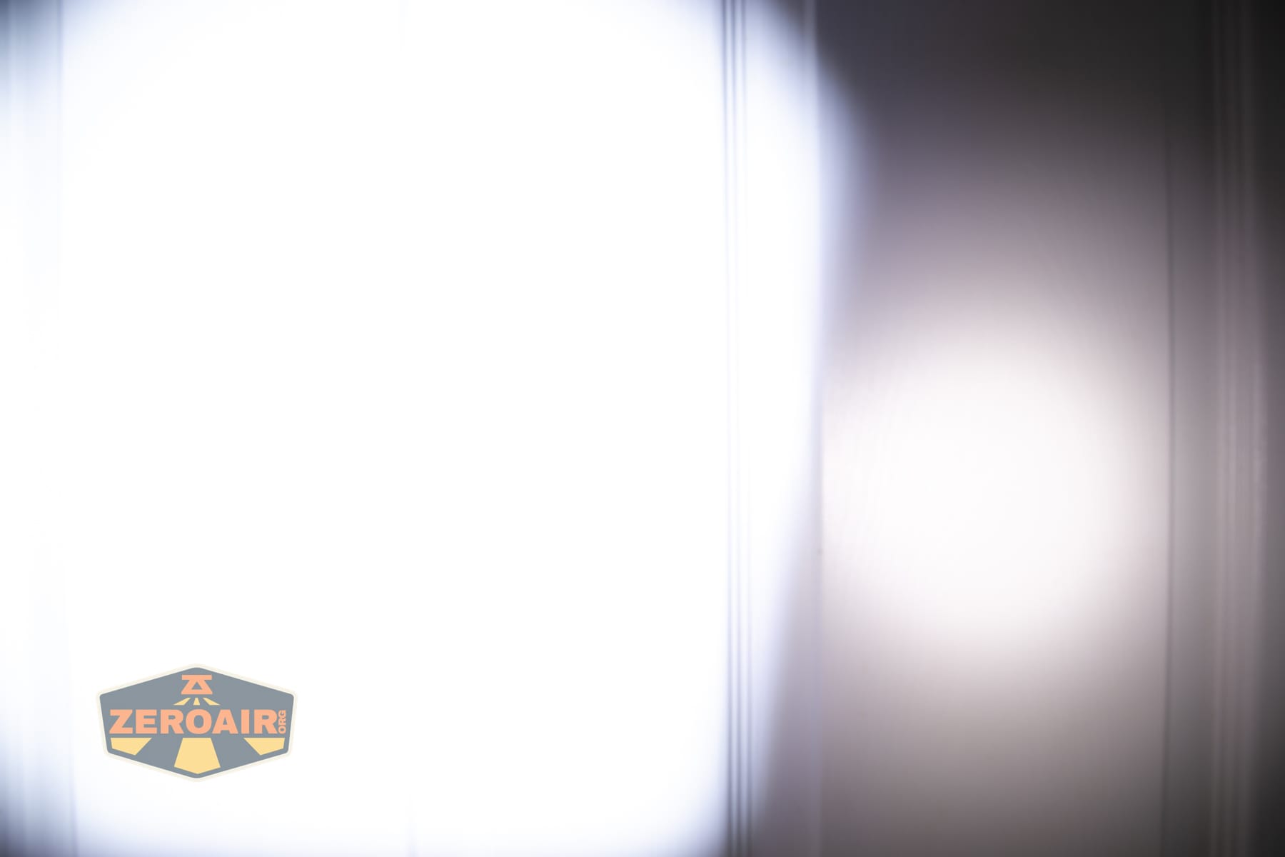 Olight Arkpro Stars and Stripes flat flashlight beamshots on door compared to Nichia 219b