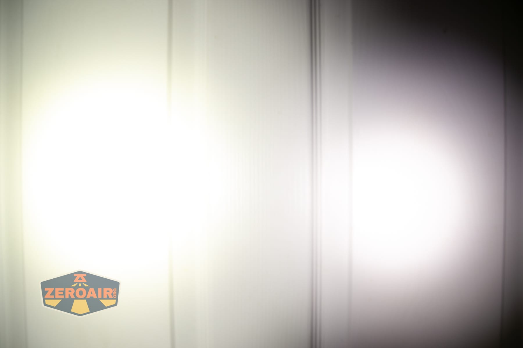 Wuben X5 3-in-1 compact EDC flashlight beamshots on door (at 1') compared to nichia 219b 4500K