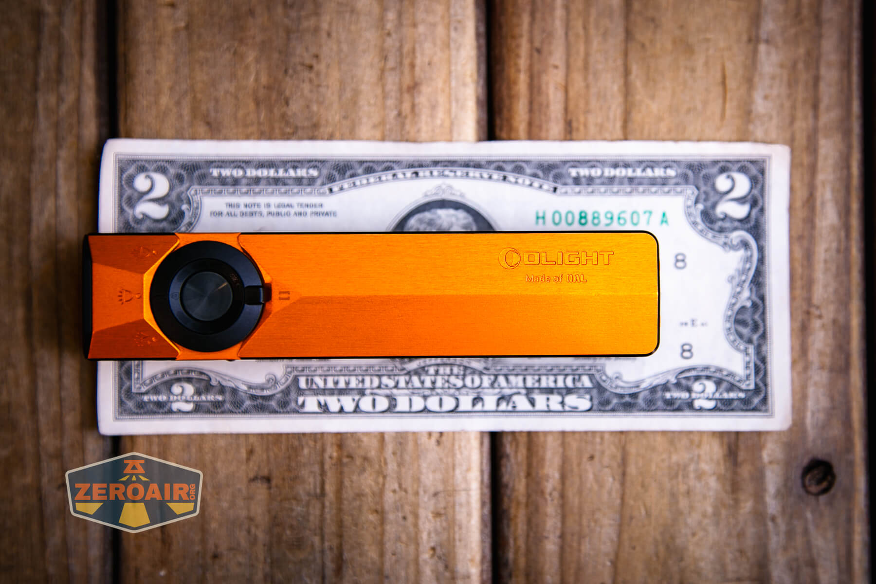 Olight ArkPro Ultra Orange flat EDC flashlight on a two dollar bill