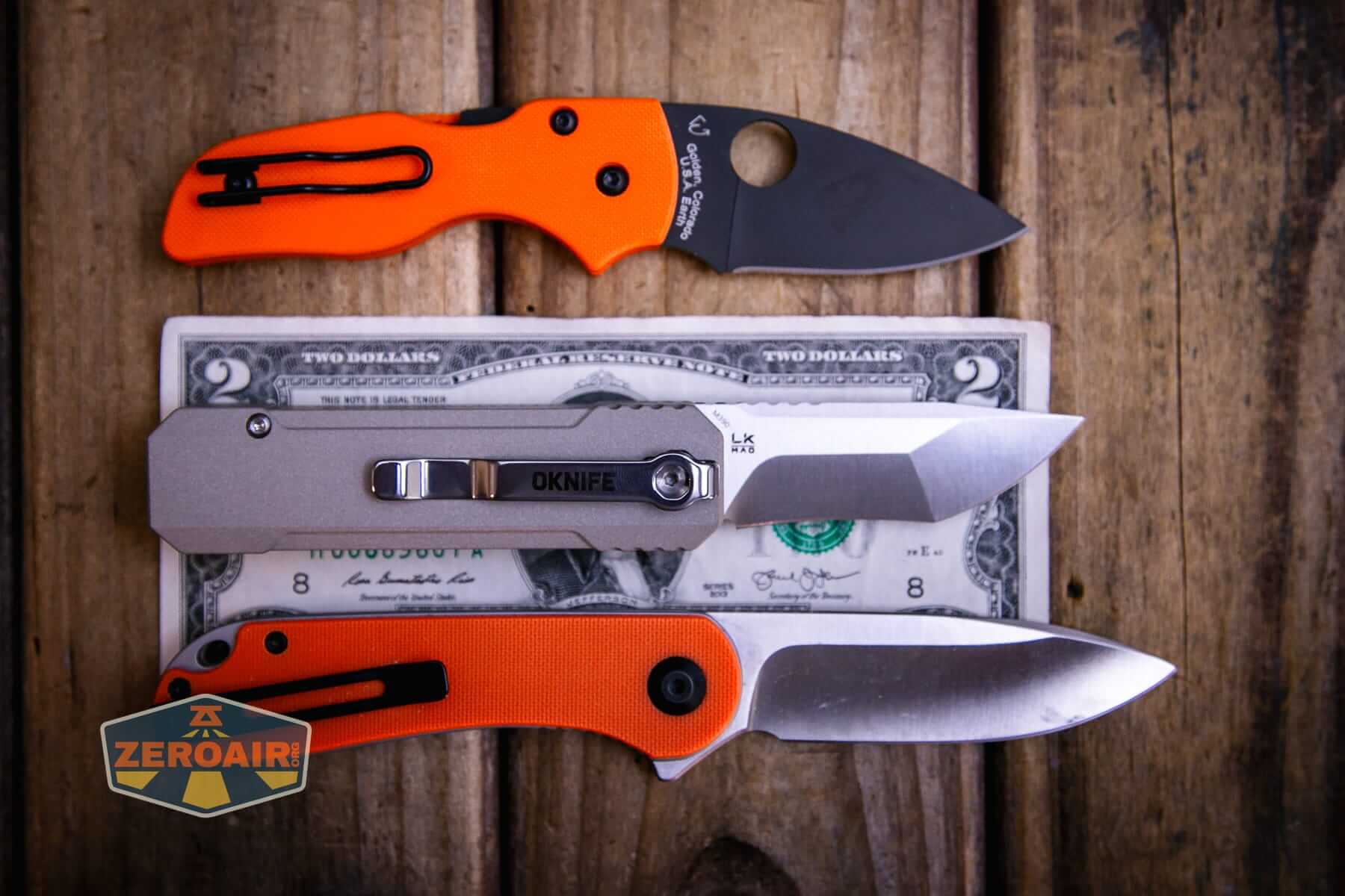 Olight Oknife LK folding knife flashlight on a two dollar bill compared to Civivi Elementum in orange