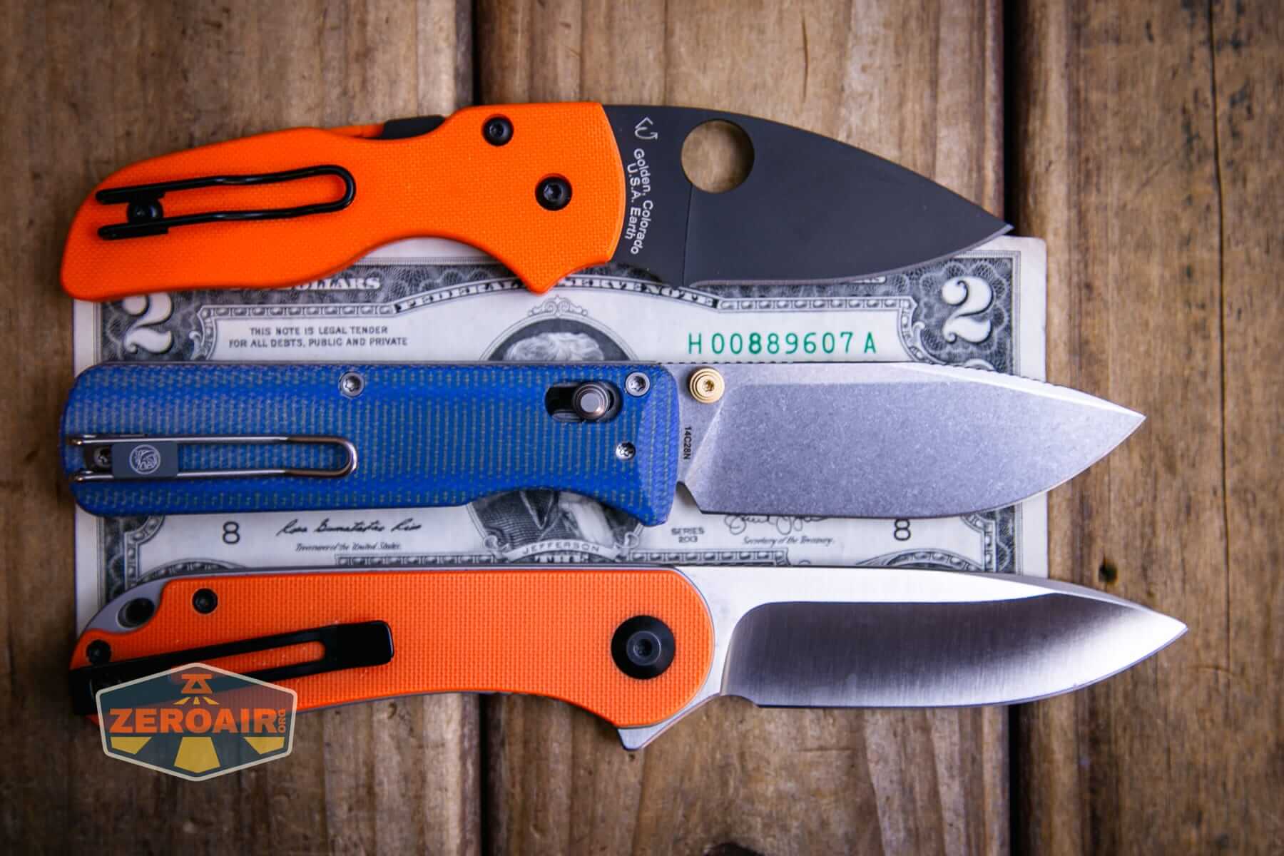 Vosteed Vombat Modswap knife on a two dollar bill compared to Civivi Elementum in orange