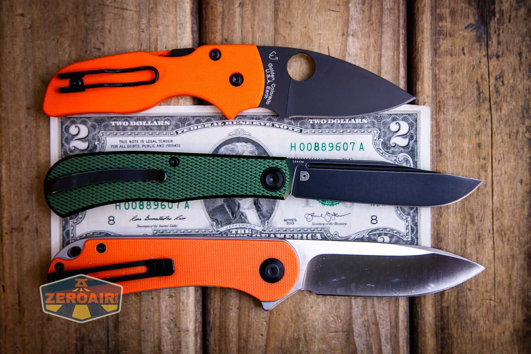 Daedalus Green Lab knife on a two dollar bill compared to Civivi Elementum in orange